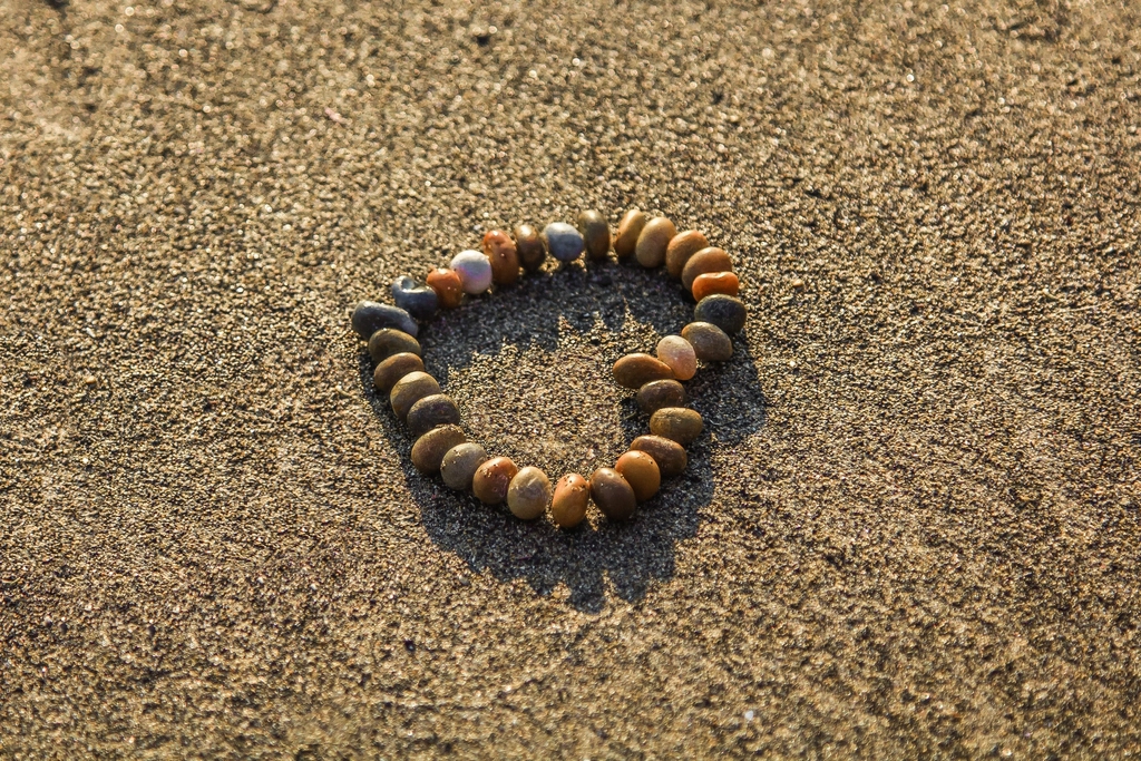 Corazón formado con piedras de colores sobre arena