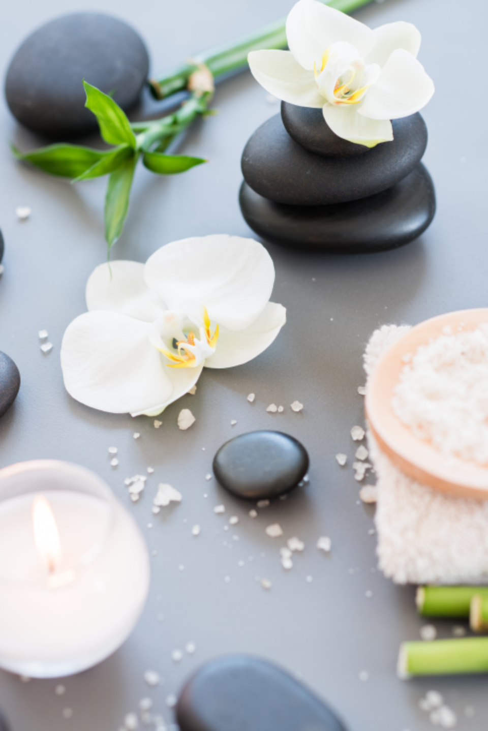 Piedras volcánicas, orquídeas, vela y sales de baño en un ambiente de spa